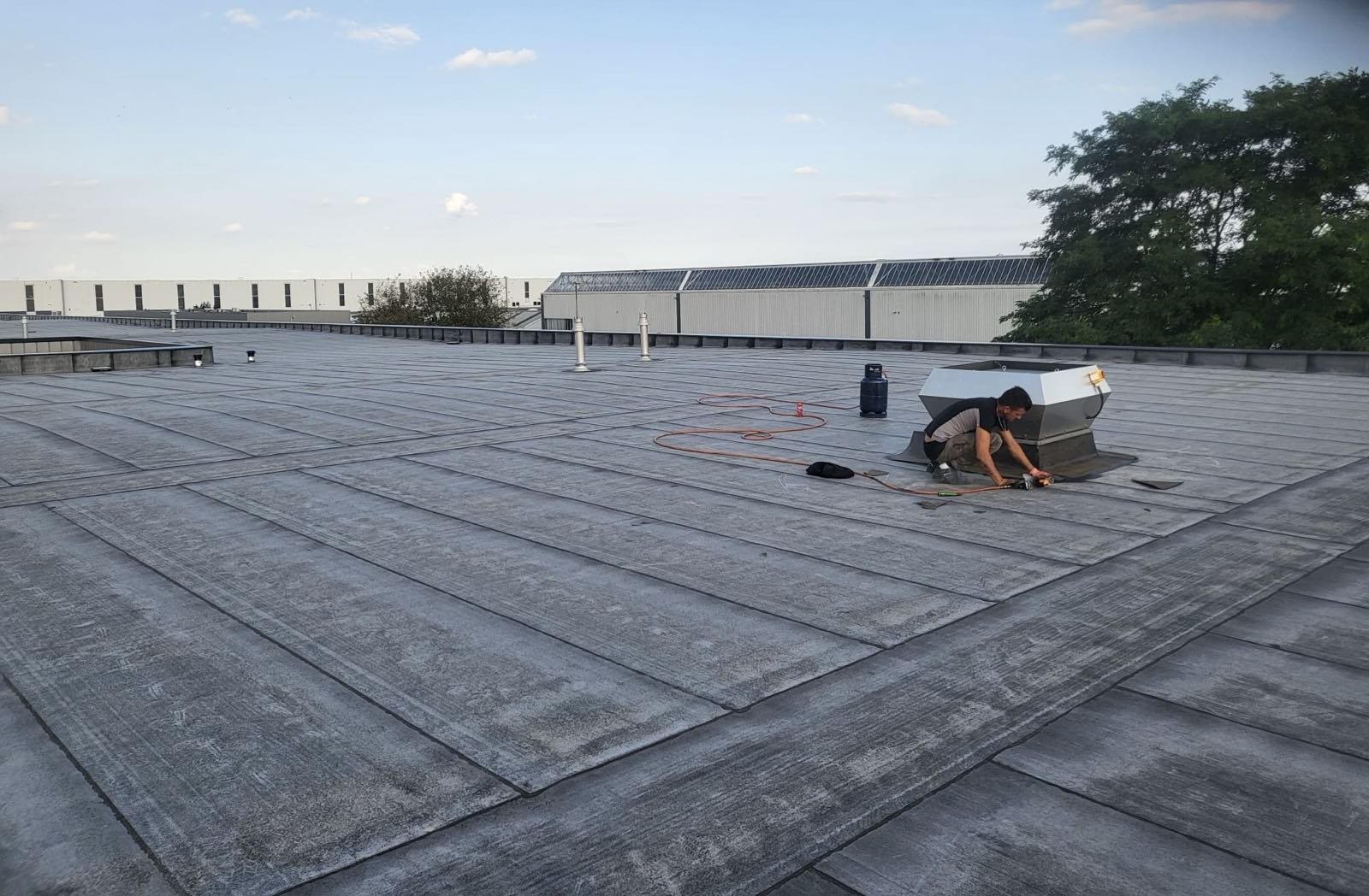 Dakdekker aan het werk op het platte dak van een bedrijfspand