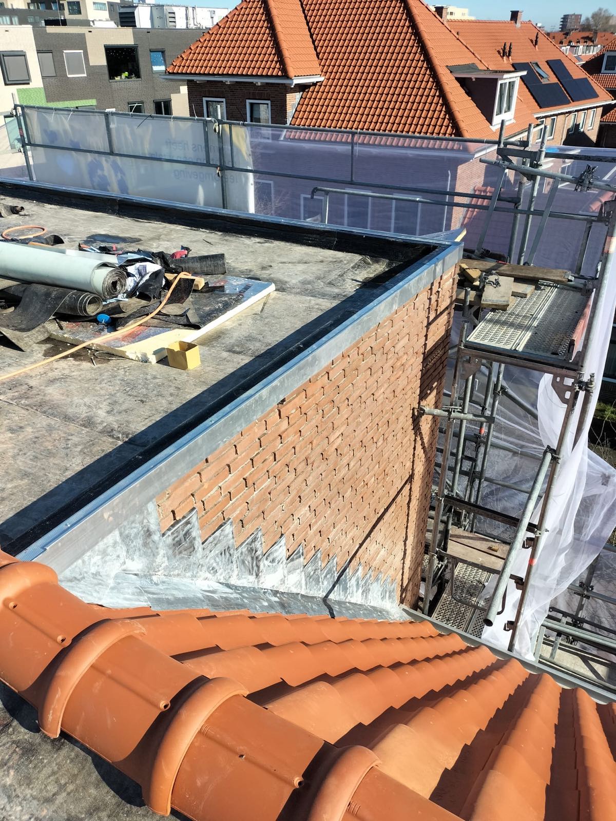 Zink- en loodwerk langs een dakrand tegen een gemetselde muur