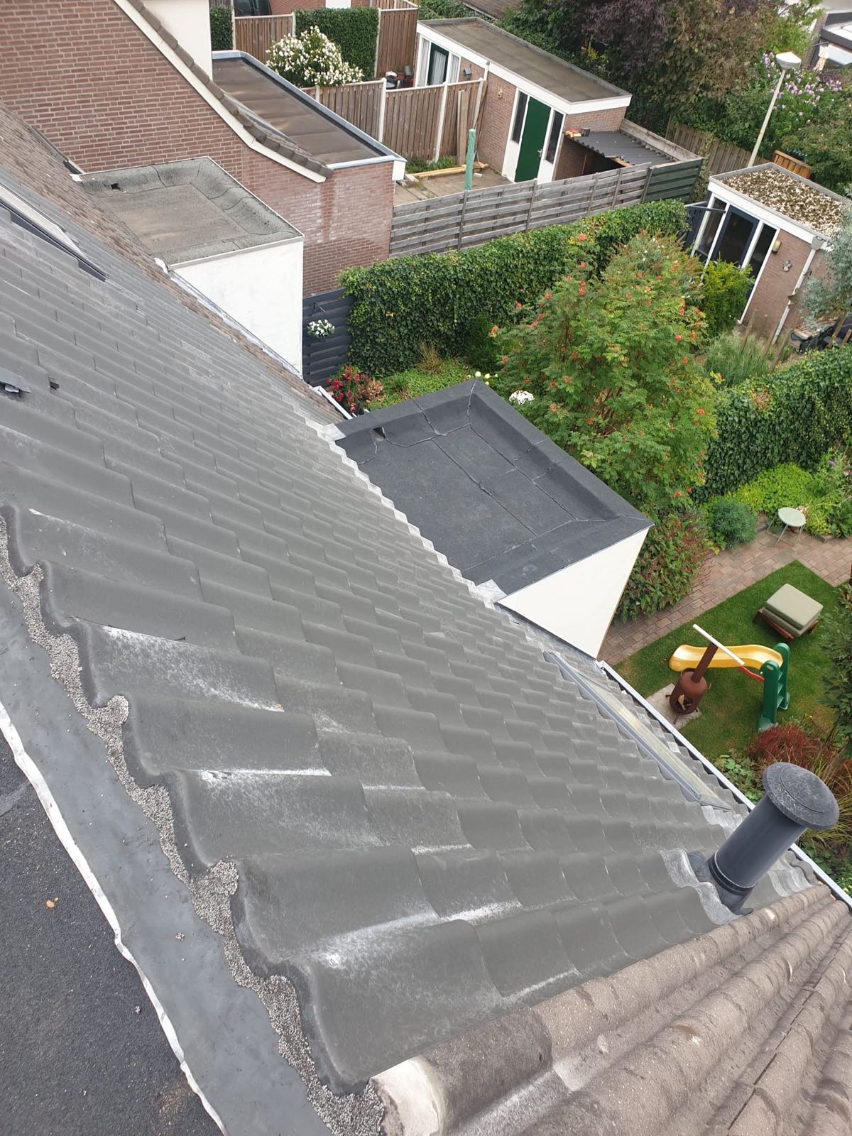 Pannendak van bovenaf, met het platte dak van een aanbouw ernaast