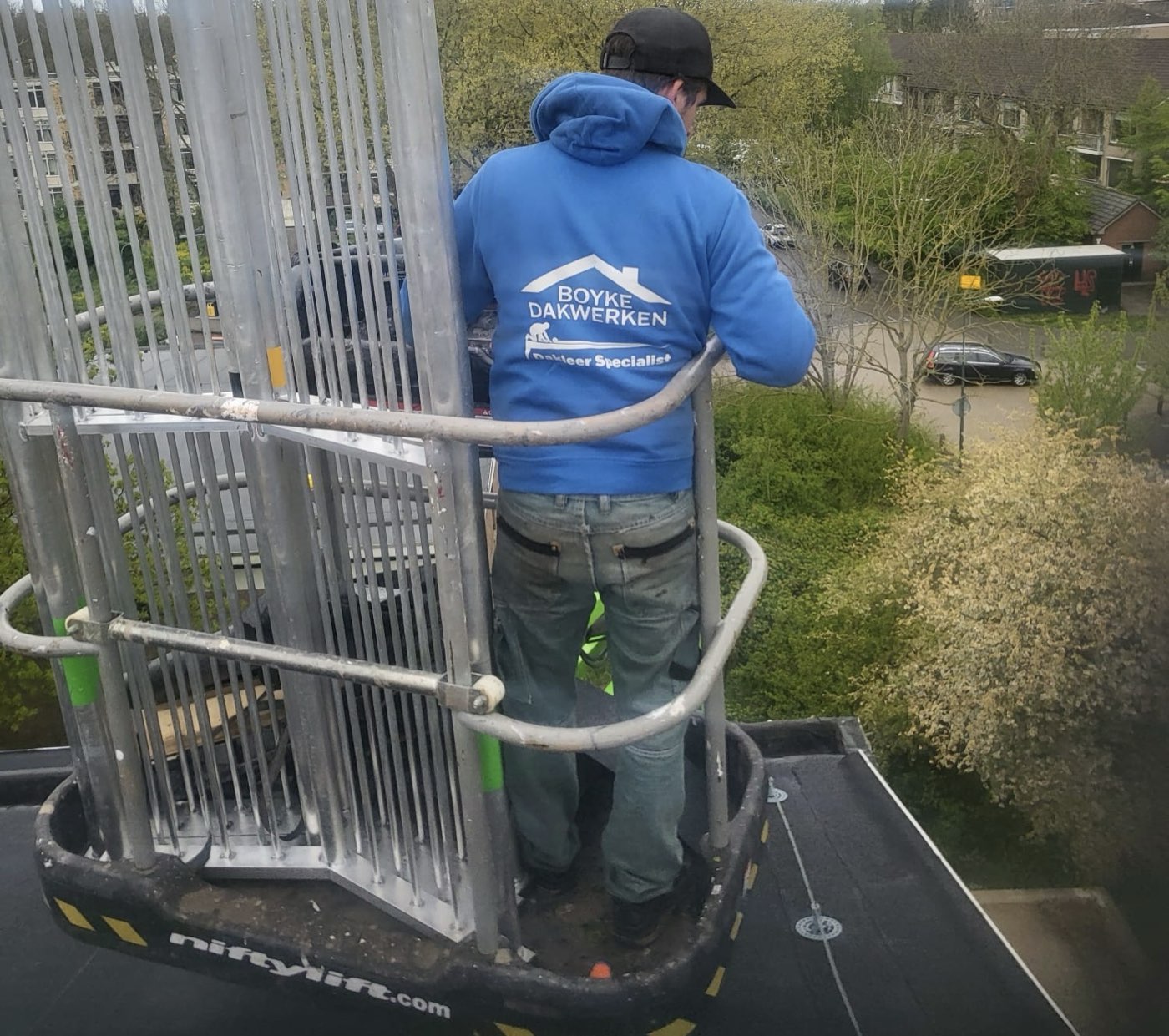 Dakdekker van Boyke Dakwerken op een hoogwerker bij een plat dak